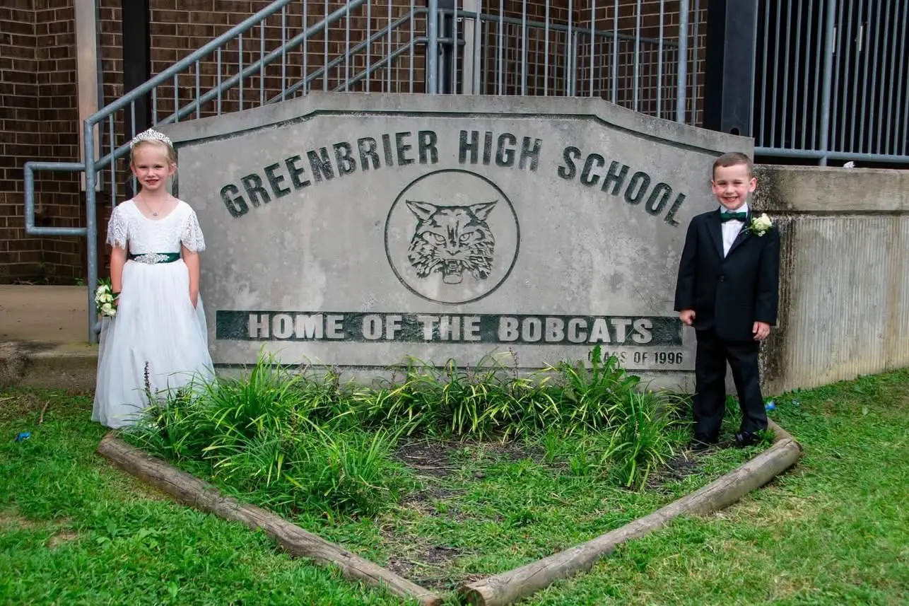 Parker Jade Sorrells and Andrew Lee Criswell dressed as junior attendants beside the Greenbrier High School sign