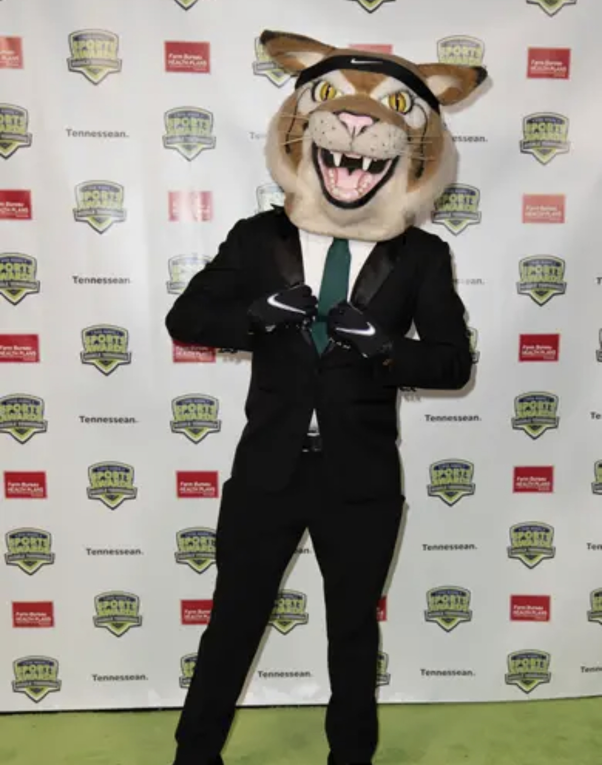 Bobby in a suit and green tie at a sports awards backdrop.